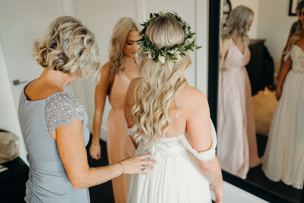 mother getting daughter into pronovias wedding dress on morning of wedding