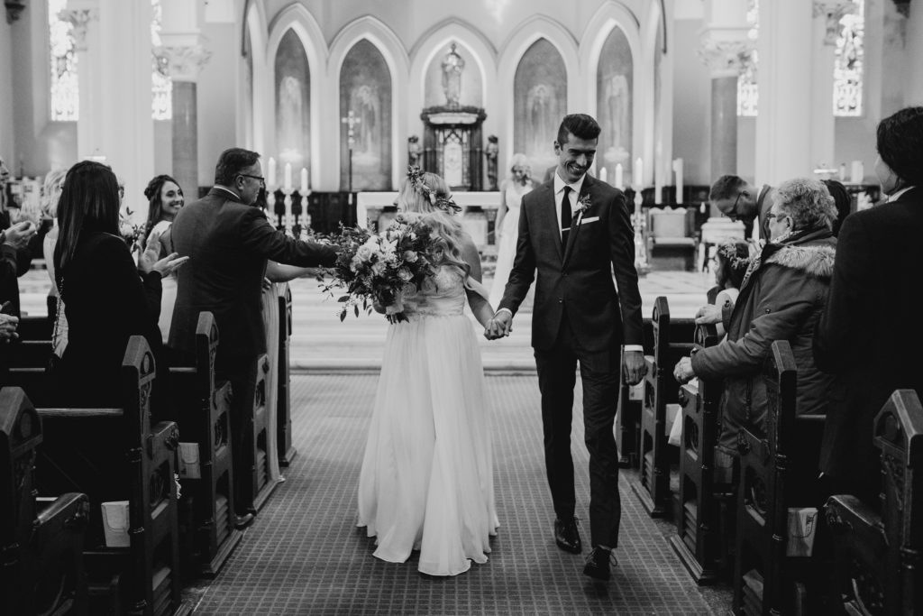 bride and groom walk down aisle at st peters basilica in london, ontario